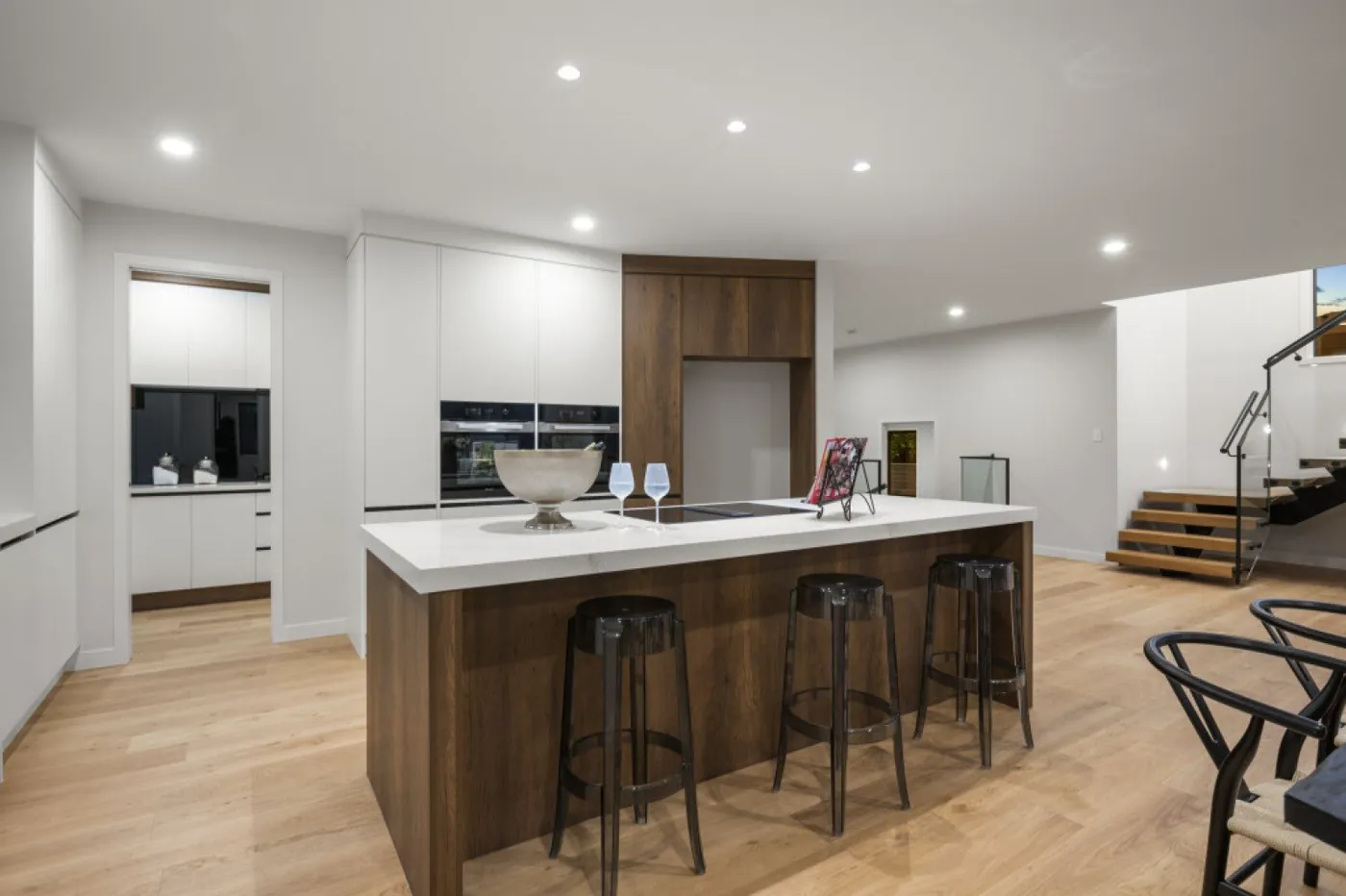 Open-plan white kitchen with timber island and black accents